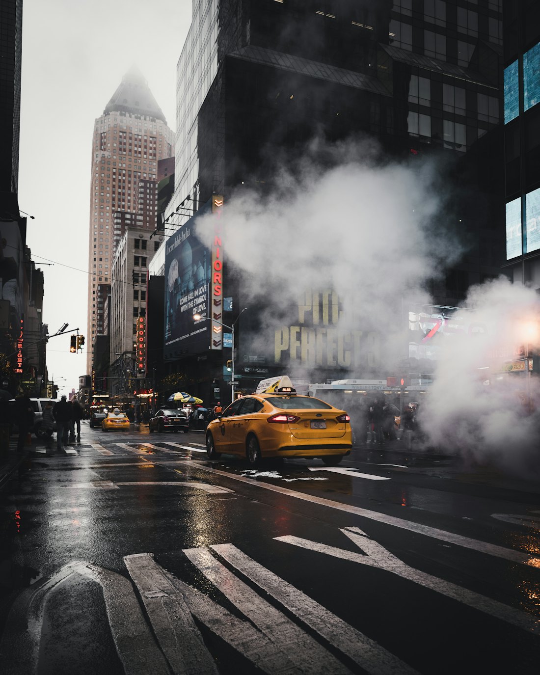 A yellow cab driving through street steam in Manhattan
